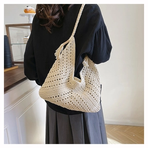 Detail of beige crochet woven shoulder bag with intricate mesh texture and tassel accent