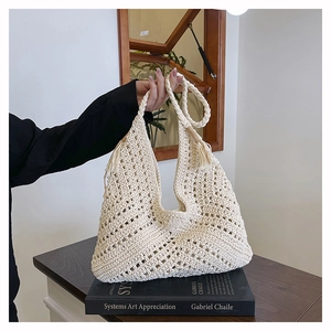 Detail of hand-woven cream tote bag featuring geometric hollow design and tassel accents
