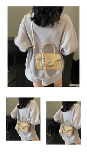 Detail showing beige crossbody bag with silver rotating lock and tassel charm accessory