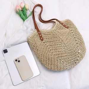 Close-up of hollow straw shoulder bag with durable brown faux leather strap stitching