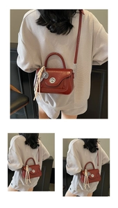 Detail of red glossy leather crossbody bag with metal rotary buckle and woven tassel