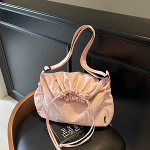 Pink drawstring nylon crossbody bag with adjustable strap on a minimalist black background
