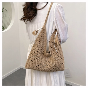 Detailed shot of hand-woven straw shoulder bag with tassel charm and crochet texture
