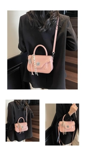 Detail of pink crossbody bag with silver twist lock and decorative scarf on a model