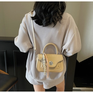 Detail of beige faux leather handbag with pleated design and metallic clasp on model