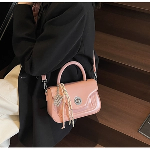 Close-up of pink leather handbag with silver twist lock and decorative scarf on wood stairs