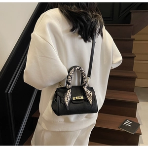 Litchi pattern leather handbag detail with golden twist lock and silk scarf on handle