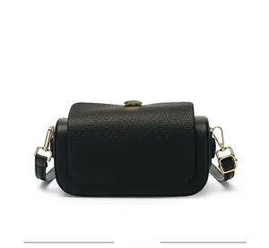 Detail shot of the woven texture and golden metal hardware on a black crossbody bag