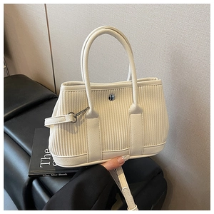 Detail of beige bucket bag with vertical stripe texture and silver metal snap button