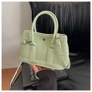 Detailed view of mint green bucket bag featuring vertical pleat texture and silver hardware