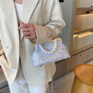 Detail of lavender shell bag with pearl handle and silver floral jacquard texture