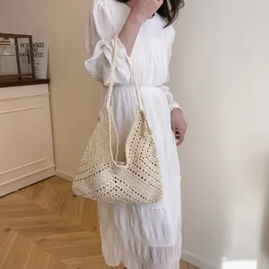 Vintage hand-woven beige tote bag with tassel charm shown on model in minimal interior