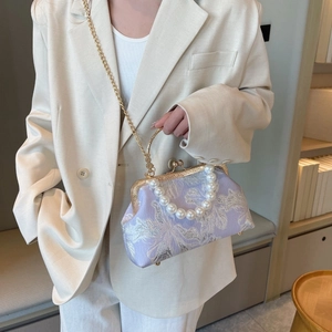 Detail of lavender shell bag with floral embroidery and elegant pearl handle