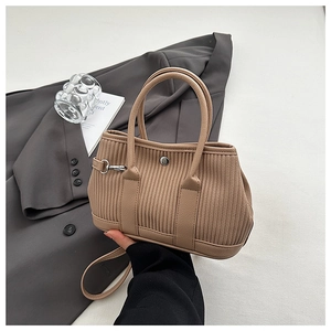 Detail of beige corduroy bucket bag with leather handles and metallic button snap closure