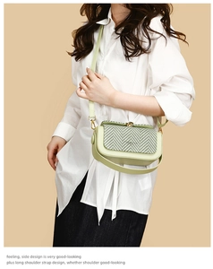 Detail view of avocado green crossbody bag with textured woven flap and adjustable strap