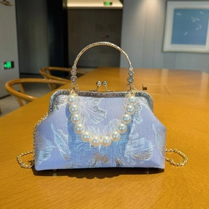Detailed view of lavender floral embroidery and vintage gold metal frame of the shell bag