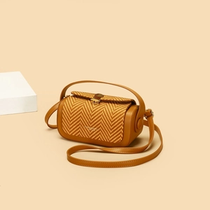 Detail of vintage cylinder crossbody bag with brown leather and herringbone straw weave