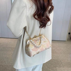 Close-up of pink shell bag with floral jacquard, pearl handle, and metal chain
