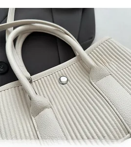 Detail of ivory bucket bag showing lychee grain leather and pleated vertical texture