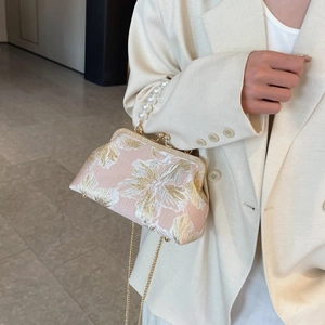 Detail of floral jacquard evening bag with pearl handle and golden chain strap