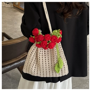 Détail d'un sac bandoulière fait main au crochet avec roses rouges sur maille crème