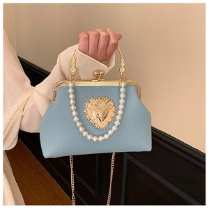 Detail of light blue pearl handle bag with gold heart relief and textured leather