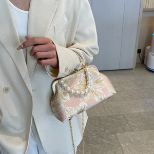 Pink floral jacquard evening bag with pearl handle and gold chain detail on model