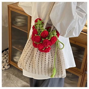 Détail du sac seau beige crocheté main avec roses rouges 3D et feuilles vertes