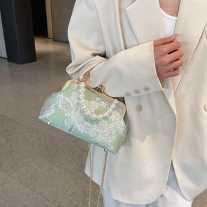 Detail of light green satin shell bag with floral embroidery and pearl handle strap