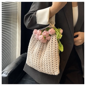 Détail du sac seau en crochet fait main avec fleurs roses et texture en tricot ajouré