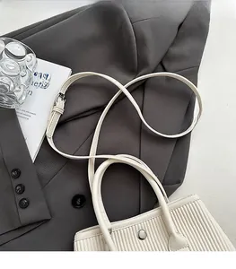 Detail of beige pleated bucket bag with adjustable shoulder strap and silver magnetic buckle