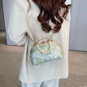Detail of light green silk shell bag with floral embroidery and elegant pearl handle