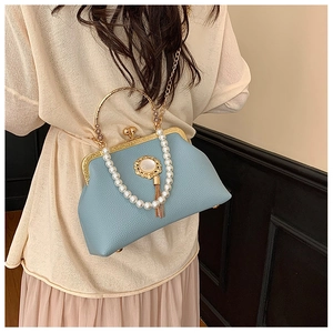 Detail of light blue lychee leather bag with gold metal handle and pearl strap detail
