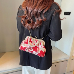 Detail of red floral embroidery evening shell bag with pearl handle and gold chain