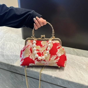 Macro detail of red floral jacquard fabric with large pearl handle and metal clasp
