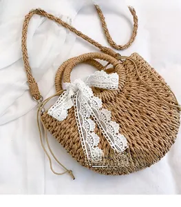 Macro detail of straw woven bag featuring a large white lace bow and drawstring closure
