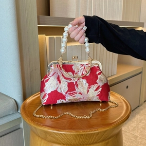 Detail of red floral shell evening bag with pearl handle and golden chain strap