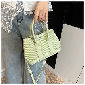 Detail of avocado green bucket bag with pleated texture and silver metallic buckle closure