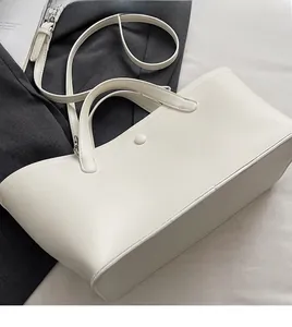 Detail shot of a white minimalist tote bag with magnetic clasp and detachable shoulder strap