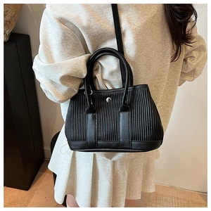 Detail of black pleated bucket bag featuring a silver metal buckle and textured leather