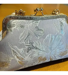 Detail of silver brocade shell bag with gold metallic frame and pearl clasp closure