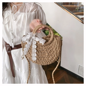 Detail of straw woven crescent bag with white lace bow and drawstring inner lining