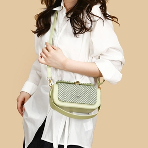 Light green crossbody handbag with woven flap and gold hardware on model