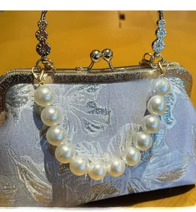 Macro detail of silver jacquard floral shell bag with large pearl strap and metal chain