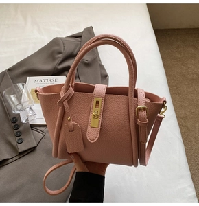 Pink lychee grain leather handbag with gold metal twist lock and shoulder strap details