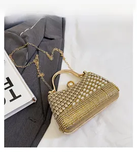 Detail of gold evening clutch bag with rhinestones, metal handle, and pearl clasp