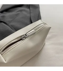 Close-up of a silver metal zipper on a beige bucket bag with detailed lychee grain texture