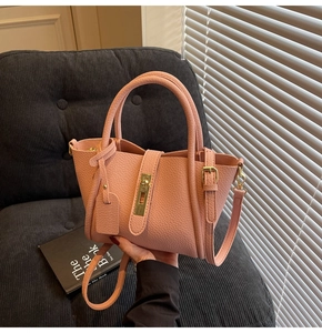 Close-up of pink lychee leather texture and golden twist lock on minimalist tote bag