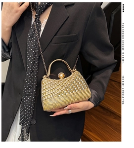 Detail of gold rhinestone evening bag with pearl clasp and chain strap held by a model