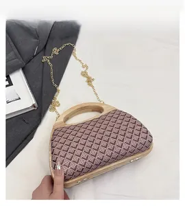 Close-up of geometric woven pattern and wooden handle on a purple trapezoid bag